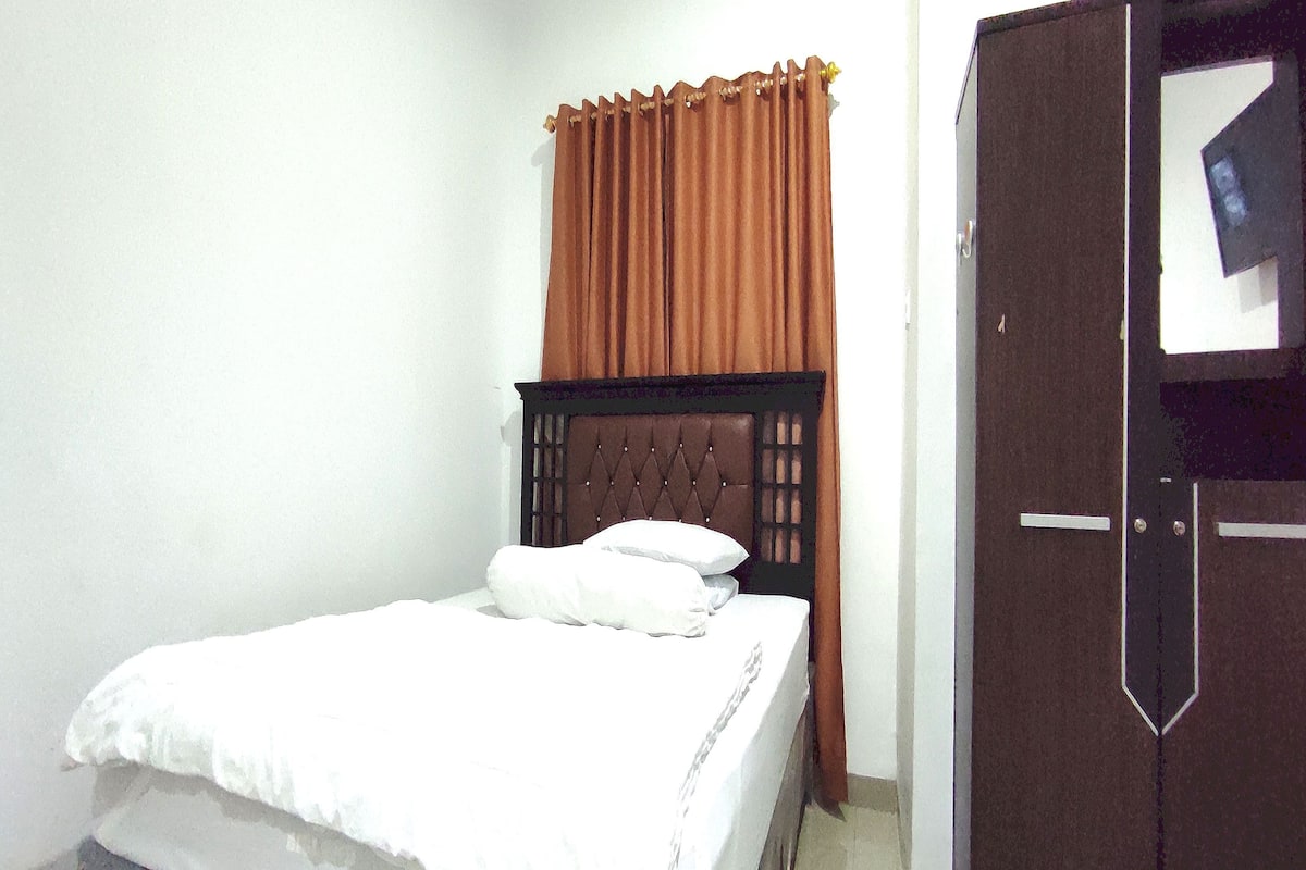 A bedroom with a bed, a wardrobe, and a curtain.