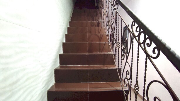 Eine Treppe mit braunen Stufen und einer schwarzen, verzierten Geländer.