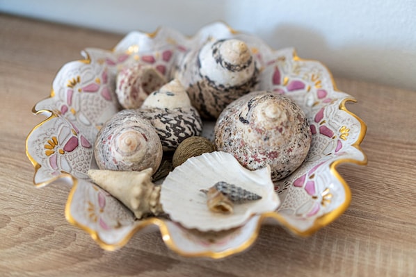 A decorative bowl with seashells and a small figurine.