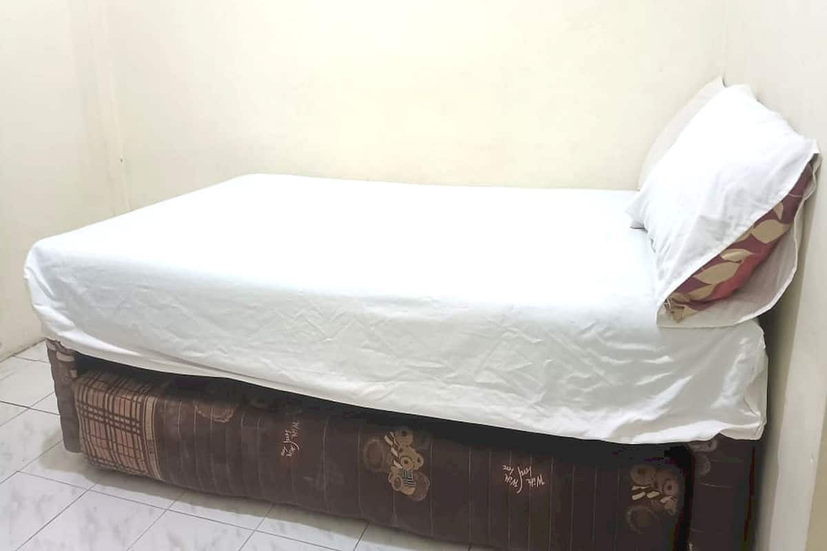A single bed with a white mattress and a patterned bed skirt.