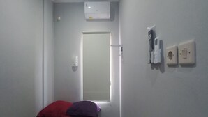A narrow hallway leading to a door, with a bed at the end. There is an air conditioning unit mounted on the wall above the door. - Hotel O Setia Budi Guest House 2 (Ngasinan Kulon)