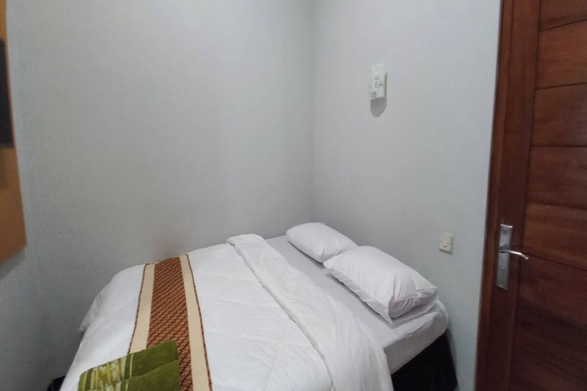 A small, neatly made bed with white bedding and a brown striped blanket.