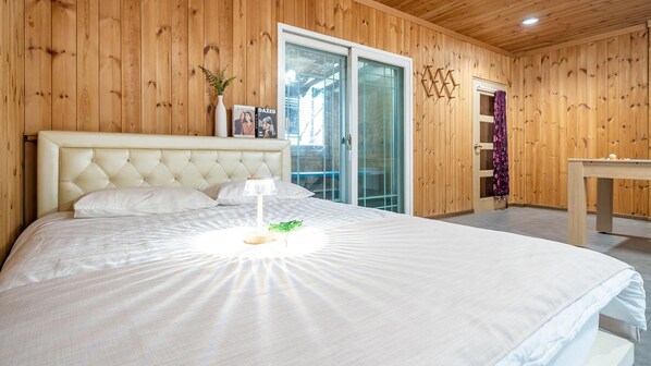 Une chambre avec un grand lit, une table de chevet et une fenêtre donnant sur un beau paysage.