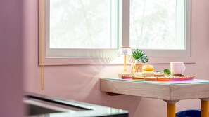 Eine gemütliche Leseecke mit einem Holztischchen, einer Lampe, einer Tasse und einer Pflanze an einem Fenster.