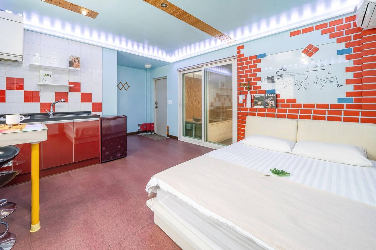 Ein kleines Hotelzimmer mit Küchenzeile, einem Bett und einem Badezimmer.