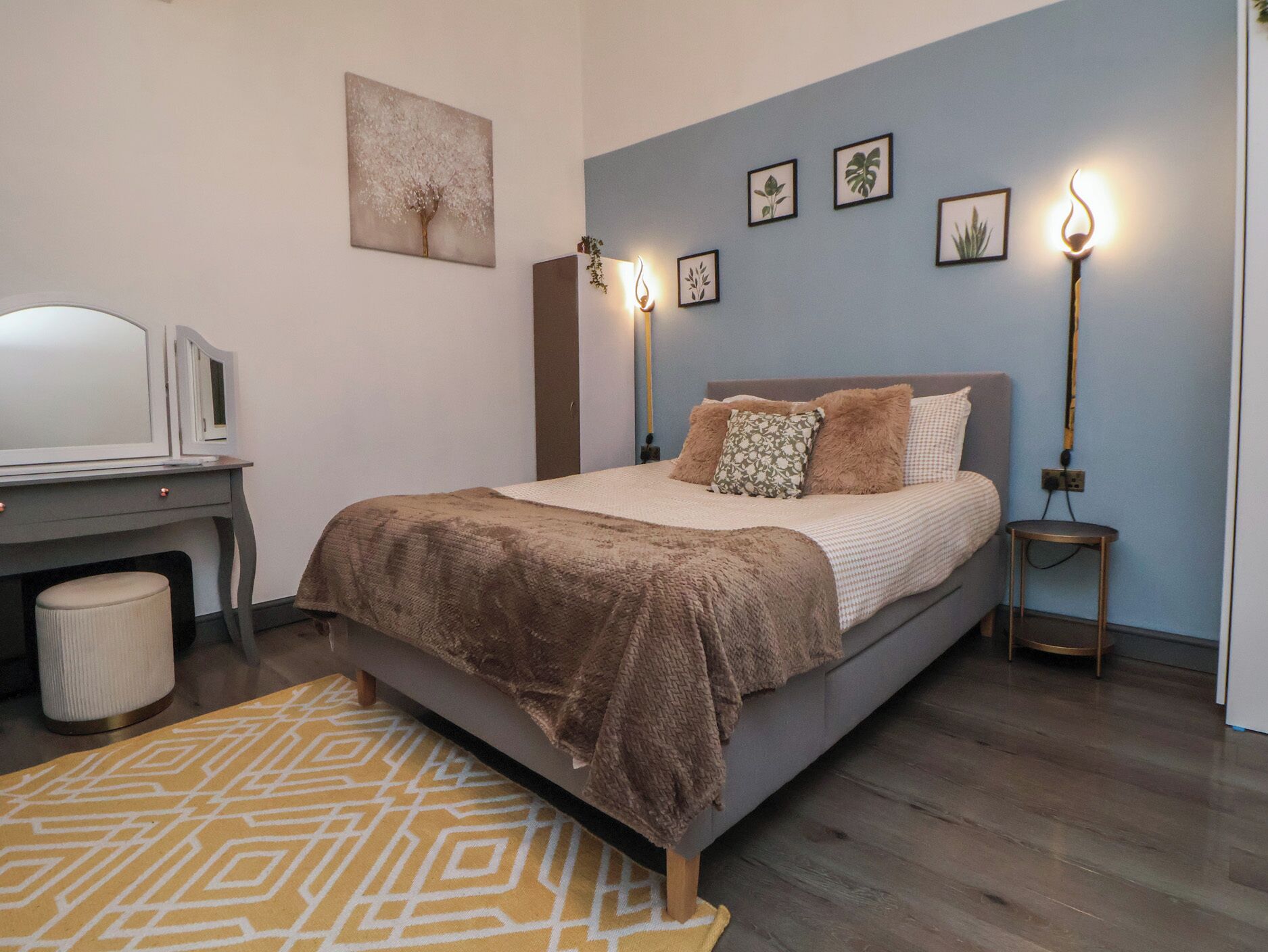 Un dormitorio con cama, lámparas de noche, escritorio y una silla.
