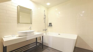 Ein modernes Badezimmer mit einem weißen Waschbecken, einer großzügigen Badewanne und einem Spiegel über dem Waschbecken.