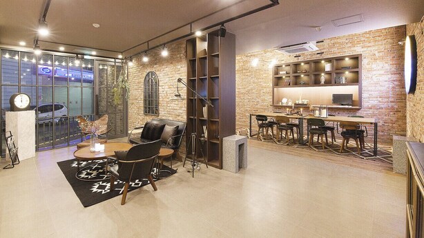Ein modernes Interieur mit Backsteinwand, rundem Tisch mit Stühlen und einem Bücherregal.
