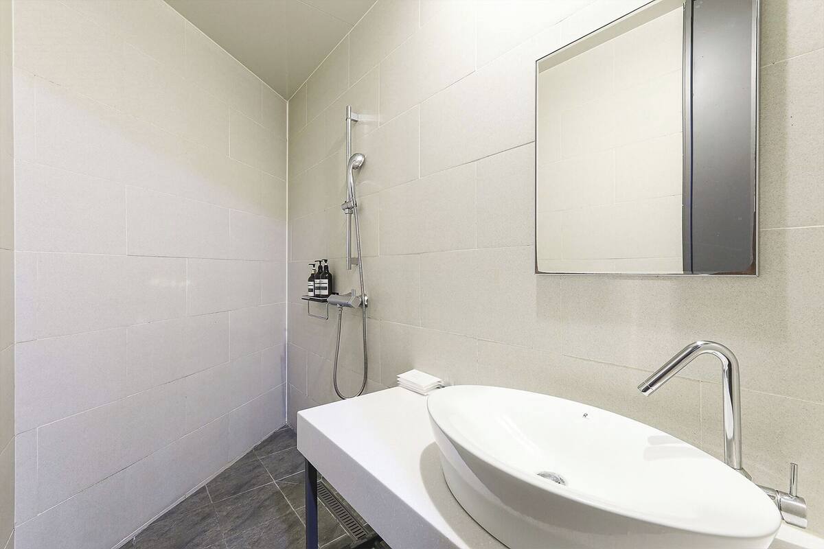 A modern bathroom with a white sink, a mirror, and a shower.
