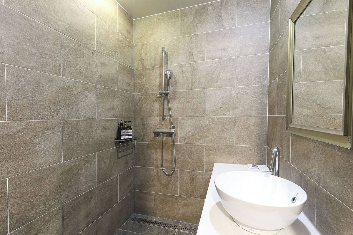 A modern bathroom with a shower, a sink, and a shelf with toiletries.