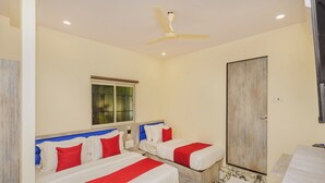 A hotel room with two beds, a ceiling fan, a window, and a door. - Hotel Good Luck Residency (Mumbai)