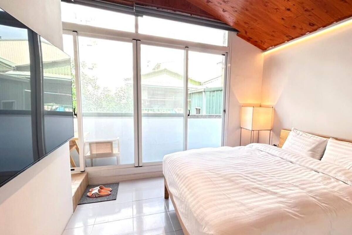 A bedroom with a bed, a nightstand, a lamp, and a sliding glass door leading to an outdoor area.