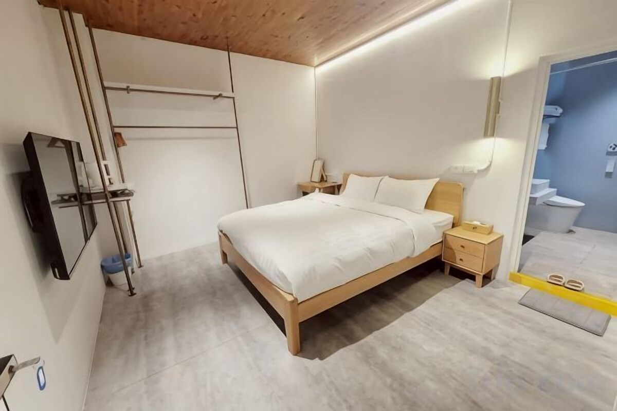 A bedroom with a bed, bedside table, and a mirror.