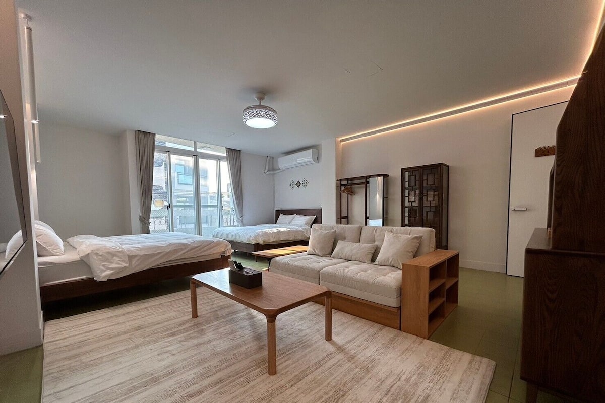 A modern hotel room with a bed, a sofa, a small table, and a wardrobe.