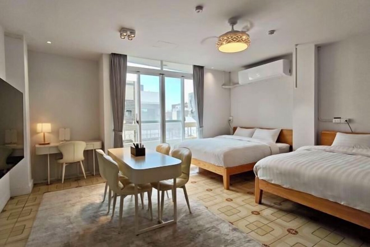 Ett hotellrum med en säng, ett skrivbord med en stol, ett bord och ett stort fönster.
