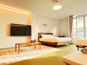 A modern hotel room with a large bed, a bedside table, a TV mounted on the wall, and a view of the city through the window. - Mansion122  (Chiayi City)
