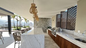 A modern kitchen with a stone backsplash, a built-in grill, and a view of the city. - Brand new Penthouse in Versalles & awesome Rooftop 2BD Penthouse for rent in Ver (Puerto Vallarta)