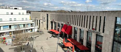 A plaza with outdoor seating and a large building with signage.