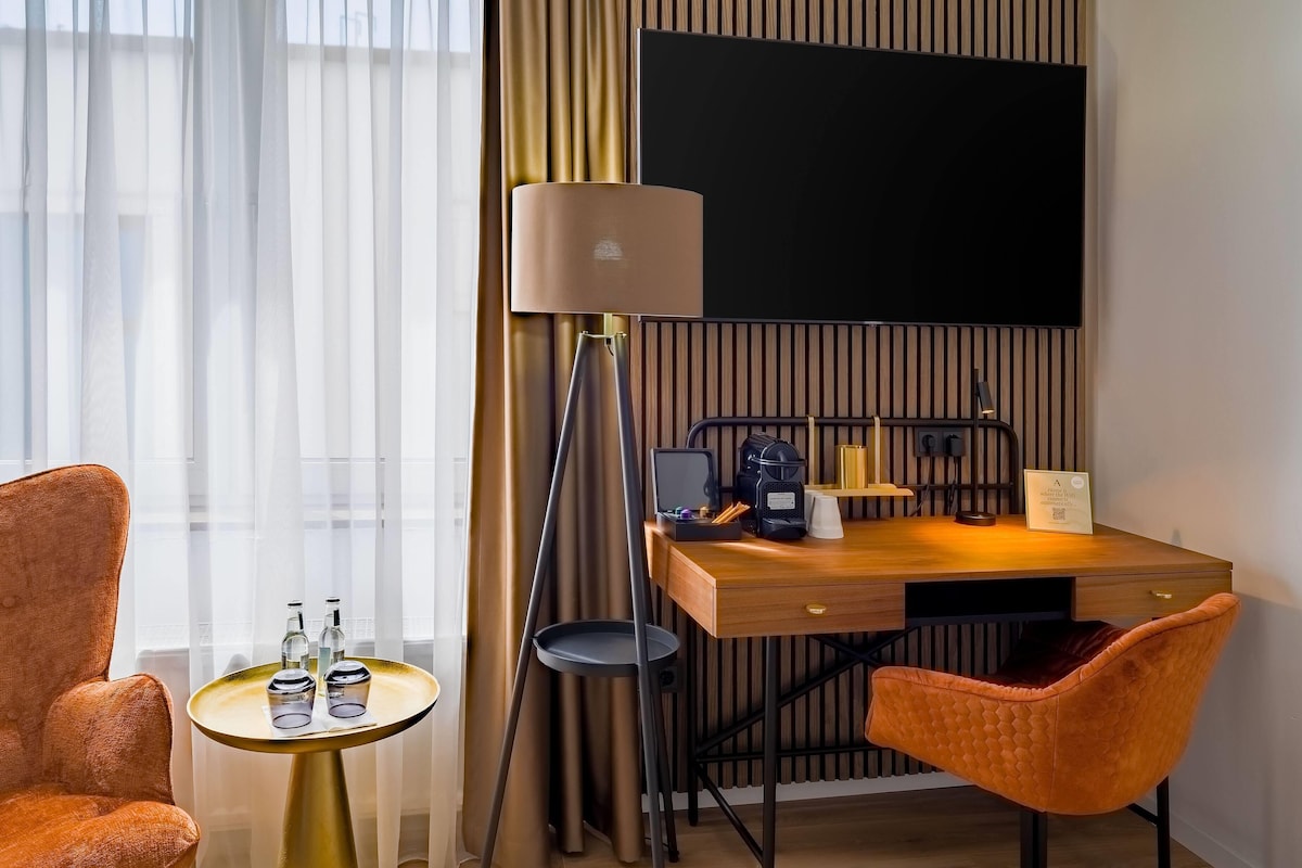 Een hotelkamer met een houten bureau, een lamp, een televisie en twee stoelen.