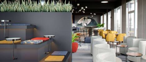 A modern hotel lobby with a reception desk, seating area, and large windows.