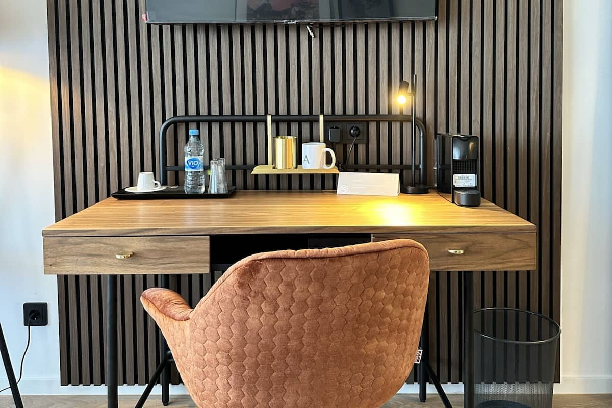 Un espace de travail moderne doté d’un bureau en bois, d’un téléviseur à écran plat et d’un fauteuil rembourré.