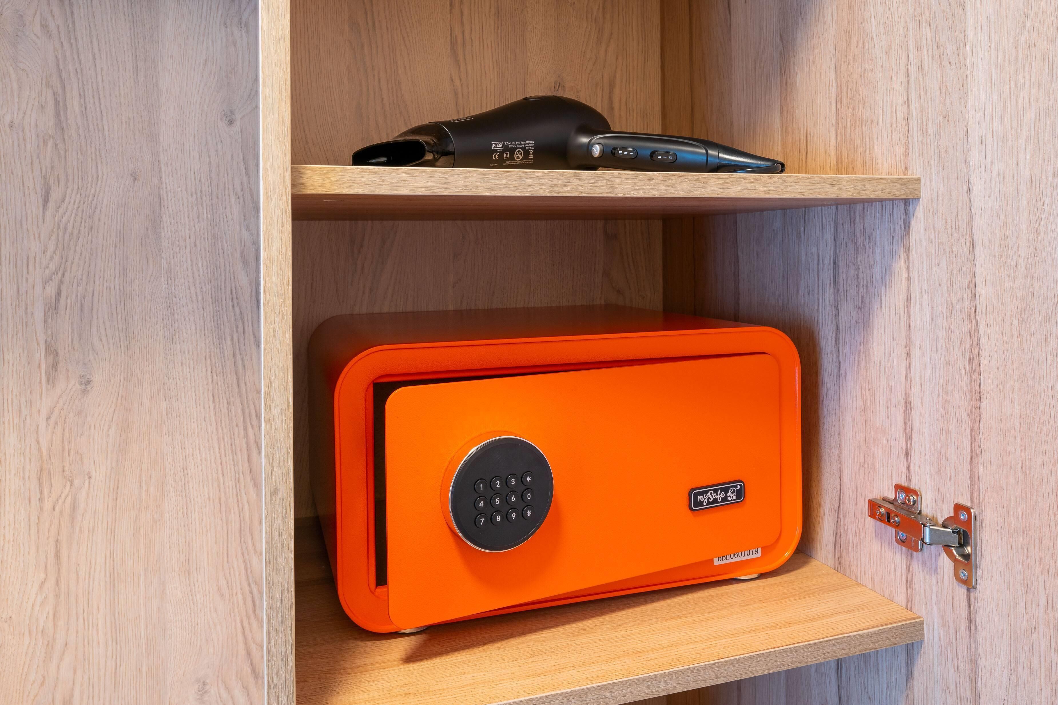 Ein Holzschrank mit einem schwarzen Ger ät auf der obersten Ablage und einem orangen Tresor auf der untersten Ablage.