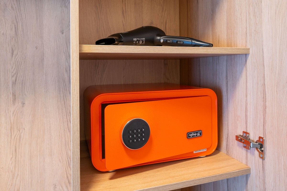 Een houten kast met een zwart apparaat op het bovenste plank en een oranje kluis op het onderste plank.