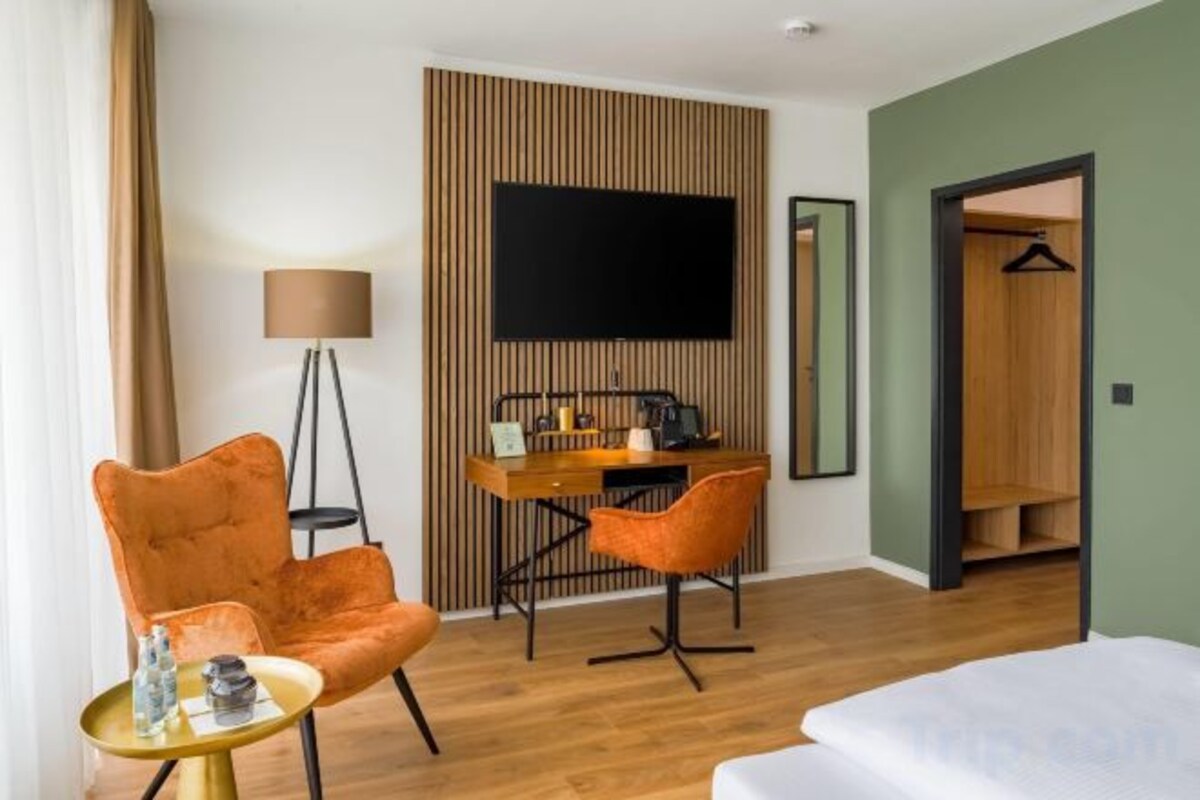 Une chambre d’hôtel comprenant un lit, un bureau, deux chaises, une télévision et une armoire.