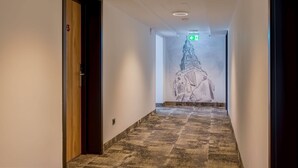 A hallway with a patterned floor, a door with a number, and a wall mural of a building. - Aspire Palais Recklinghausen,Trademark Collection by Wyndham (Recklinghausen)