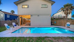 A two-story house with a swimming pool, outdoor seating, and a wooden fence. - Private Pool, in Golf Cart Zone, Golf Cart for Rent | Sea Therapy by AvantStay (Port Aransas)