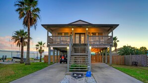 A two-story house with a balcony, a garage, and a driveway leading to the entrance. - Private Pool, in Golf Cart Zone, Golf Cart for Rent | Sea Therapy by AvantStay (Port Aransas)