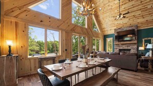 A spacious wooden dining area with a long table set for six, benches, and a fireplace. - The Lodges | AvantStay | Lakefront, Sleeps 66 | Pools, Docks, Theaters, Views (Sherrills Ford)