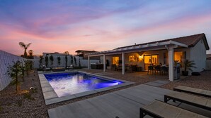 A modern outdoor pool area with a patio, seating, and a covered section with a kitchen area. - Montego by AvantStay | Private Yard w/ Pool & Hot Tub (Indio)