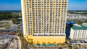 Un hotel moderno de gran altura con varios balcones, piscina y vistas panorámicas del entorno.