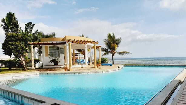 Une piscine dotée d’un espace détente abrité et offrant une vue sur la mer.