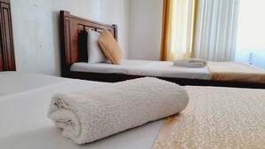 Une chambre d’hôtel avec un lit bien fait, une tête de lit en bois et une fenêtre avec des rideaux.
