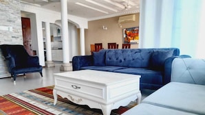 Un salon moderne avec un canapé bleu, une table basse blanche et un tapis à motifs.