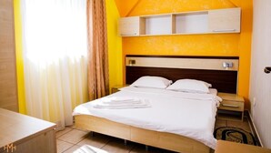 Habitación de hotel con cama, mesita de noche y estante empotrado sobre la cama.