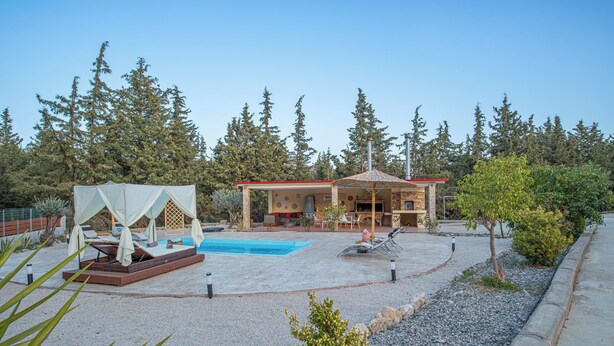 A resort with a pool, outdoor seating, and a building with a red roof.
