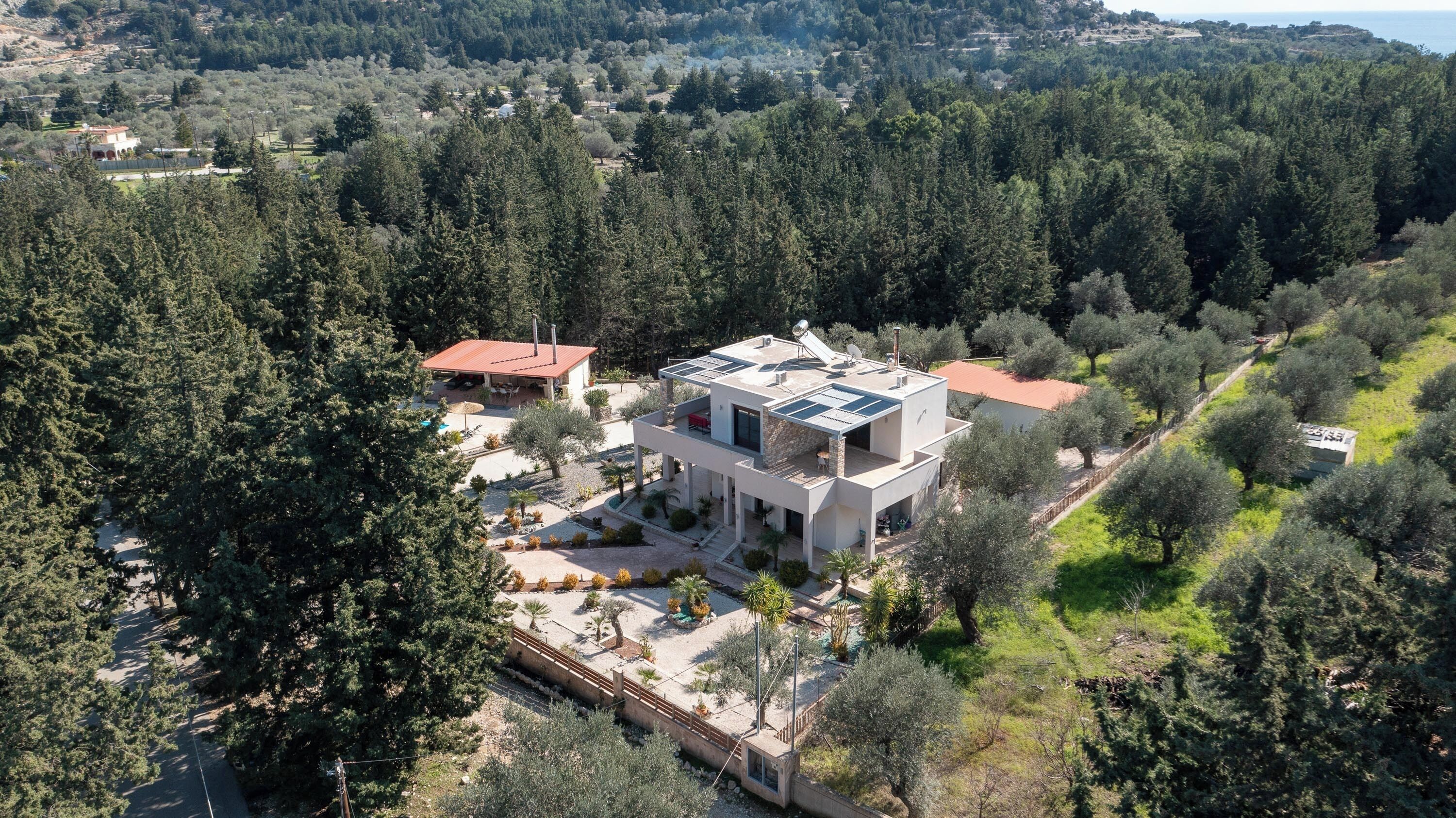 A modern house with a flat roof, surrounded by dense forest.