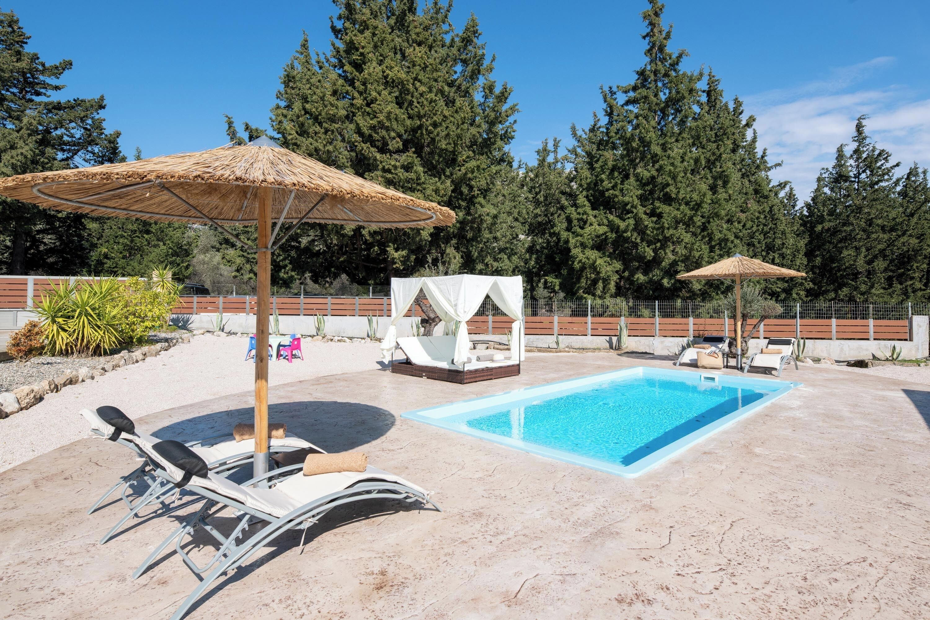 Ein Poolbereich mit Liegestühlen, Sonnenschirmen und einer kleinen weißen Laube.
