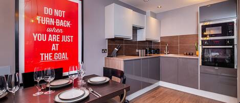 A modern kitchen with built-in appliances, a dining area with a motivational poster, and a wooden floor.