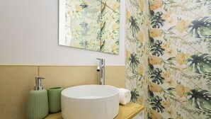 Un baño con un lavamanos blanco y redondo, un espejo y una encimera de madera.