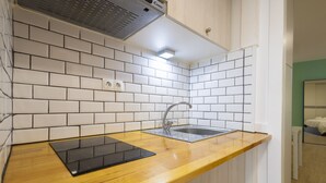 Una cocina con salpicadero de azulejos blancos, encimera de madera, un lavabo y una tablet negra.