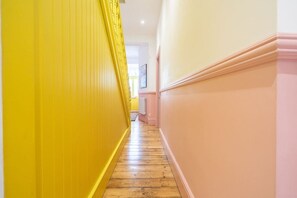 A hallway with wooden flooring and yellow and pink walls.