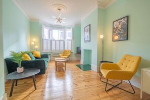 A living room with a green sofa, yellow armchair, and a small table with a plant. - Broadstairs ColourPop | Parking | Beach/Bars 2 min (Kent)