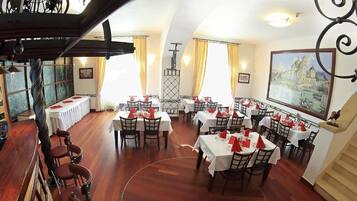 Un comedor con mesas dispuestas para el servicio, una zona de bar con taburetes y una escalera que conduce a un nivel superior.