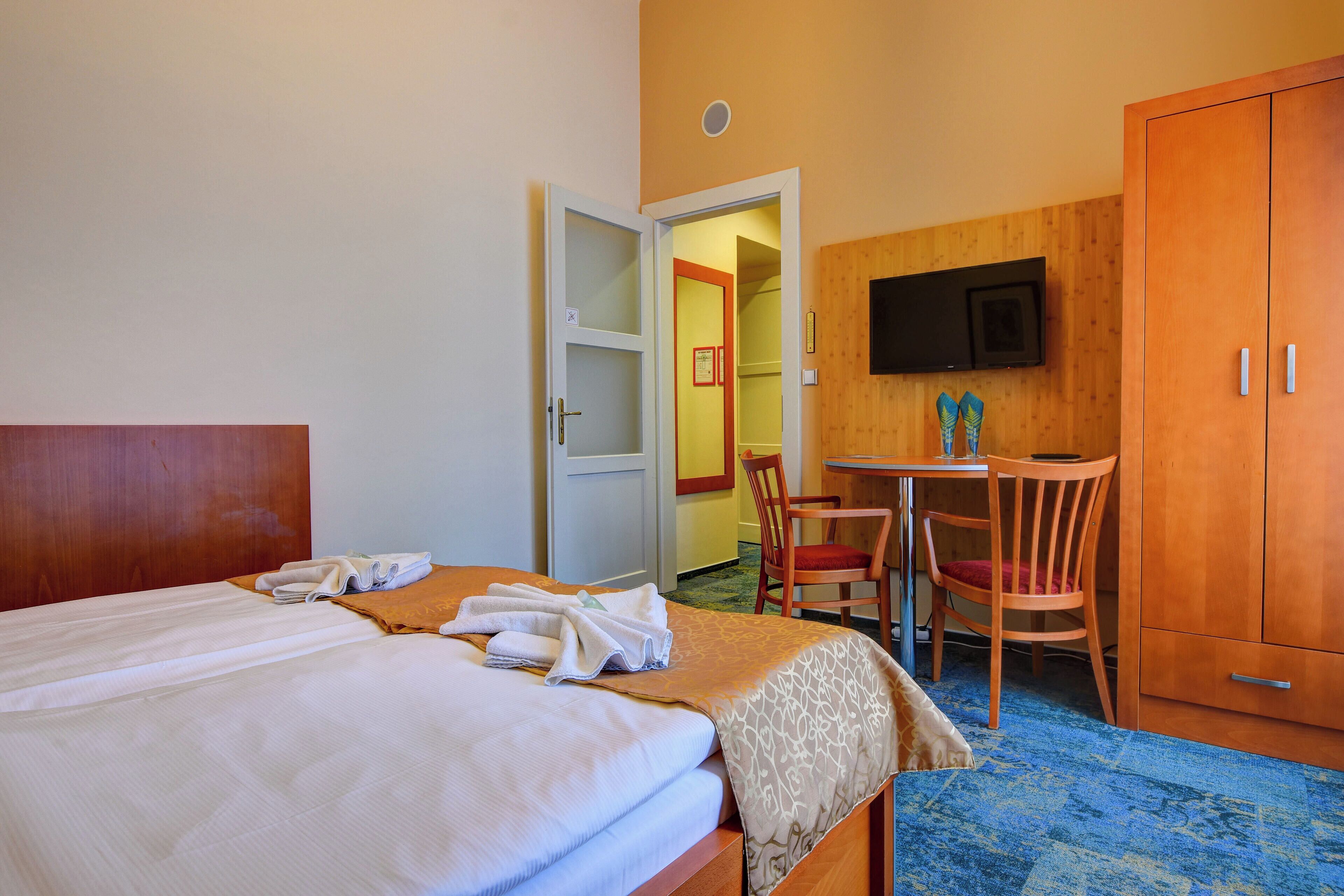 A hotel room with a bed, a desk, a chair, and a wardrobe.