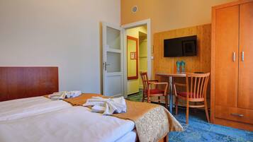 A hotel room with a bed, a desk, a chair, and a wardrobe.