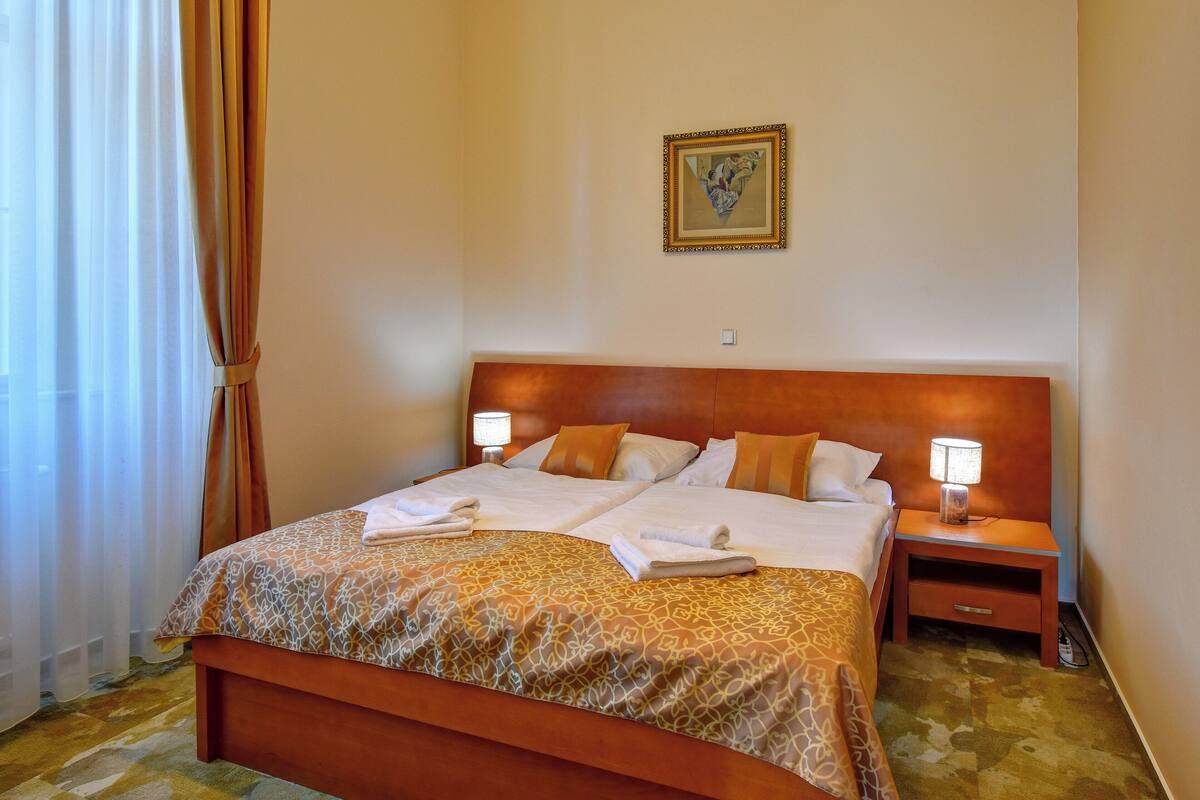 A hotel room with a large bed, two bedside tables with lamps, and a framed picture on the wall.